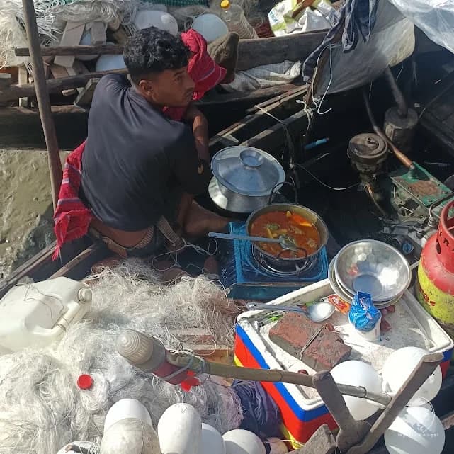 **Fisherman cooking his meal on a small boat in the Sundarbans**